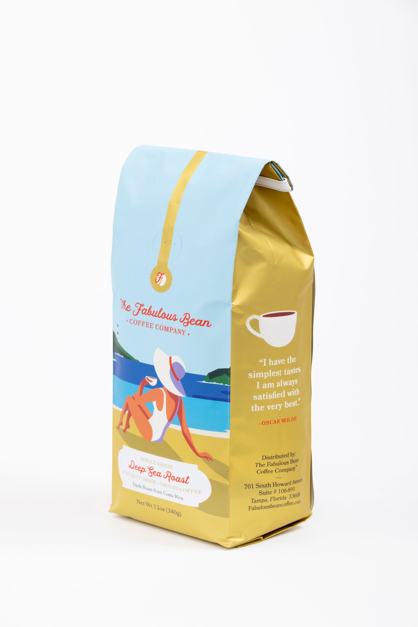 Specialty-grade dark roast ground coffee from Costa Rica in a colorful 12 ounce bag with the front panel depicting a sophisticated lady in a modest one piece bathing suit and floppy hat enjoying a cup of coffee on a beautiful beach against a background of  light blue sky, green covered hills, an azure sea and golden sand. 