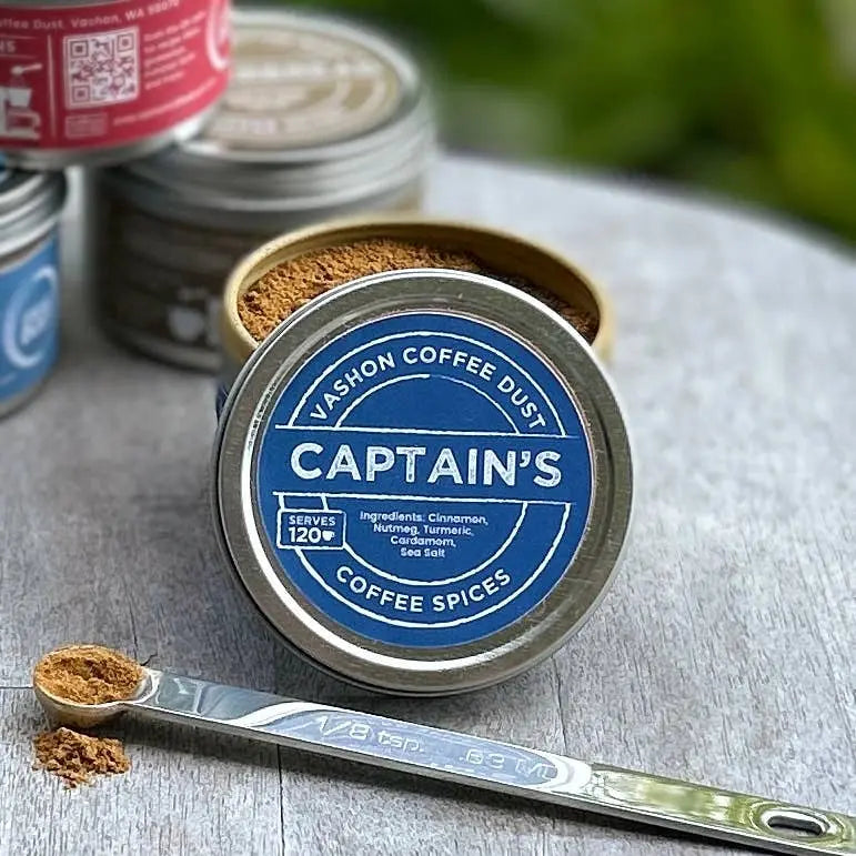 Vashon Island Captain's coffee dust container with a spoonful of ground spices on a wooden surface. Container lid indicates 20 servings.