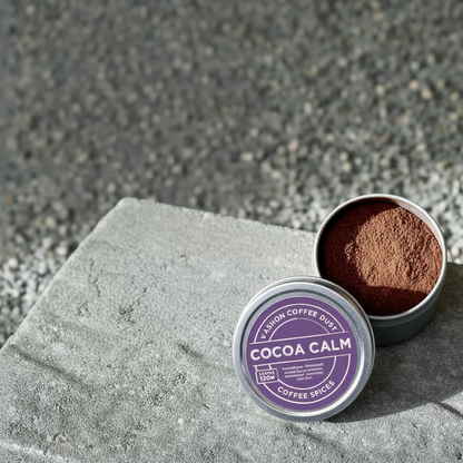 A full-size tin of Cocoa Calm coffee dust from Vashon Island Coffee Dust. Provides 120 servings. Presented on a textured surface.