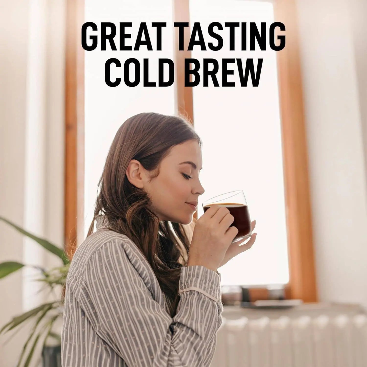 Attractive young woman holding a clear glass mug of cold brew coffee made with the Zulay Cold Brew Coffee Maker in 32 ounce size.