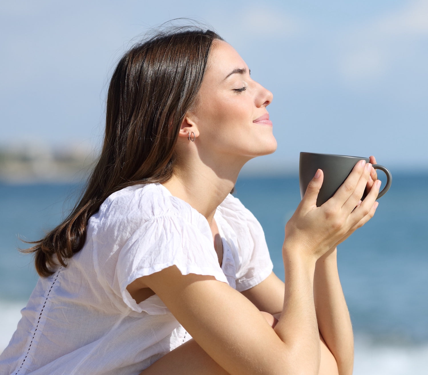 Fabulous Bean Coffee image of an attractive young woman enjoying Fabulous Bean Coffee on a beautiful beach