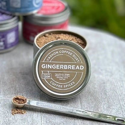 Vashon Island Gingerbread flavor coffee spice mix in full-size tin with a measuring spoon alongside it on a wooden surface.