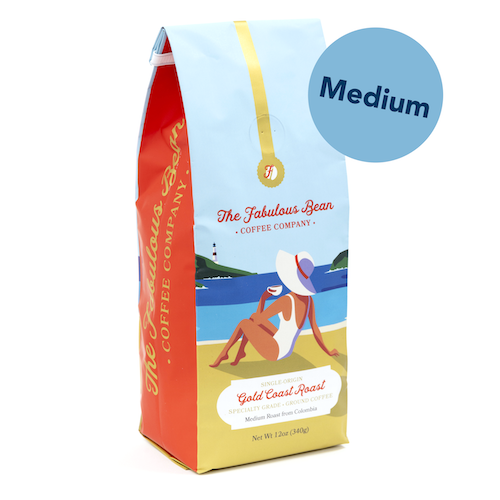 Fabulous Bean Coffee's Gold Coast Medium Ground Roast in a 12 ounce bag featuring a sophisticated woman enjoying coffee on a beautiful beach