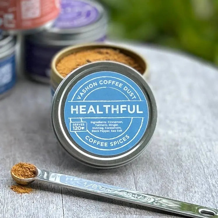 Full size tin of Vashon Island 'Healthful' coffee dust with a measuring spoon on a wooden surface. The product label indicates 120 servings.