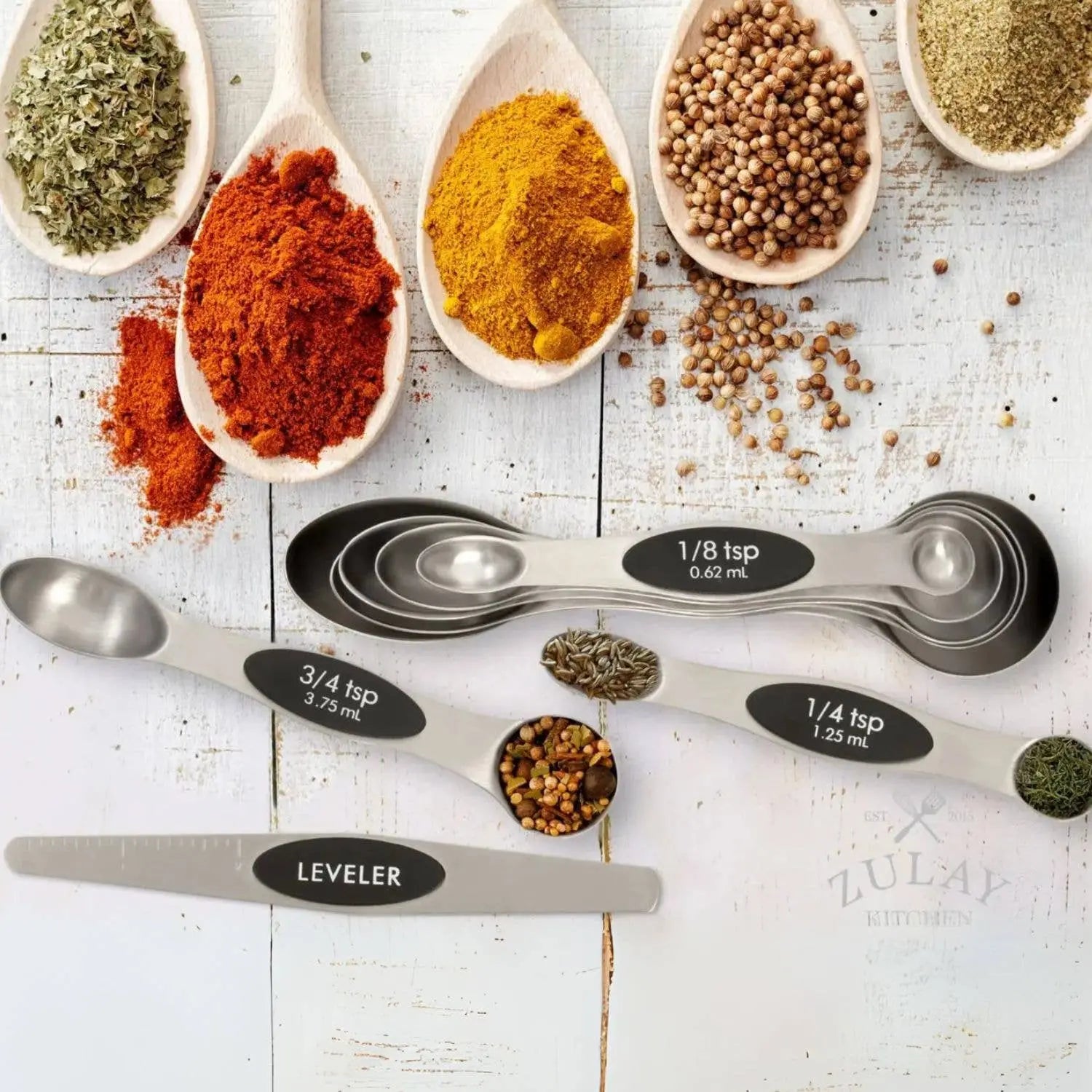 Measuring set of 8 dual-sided spoons for measuring both liquid and solid ingredients set against white surface.