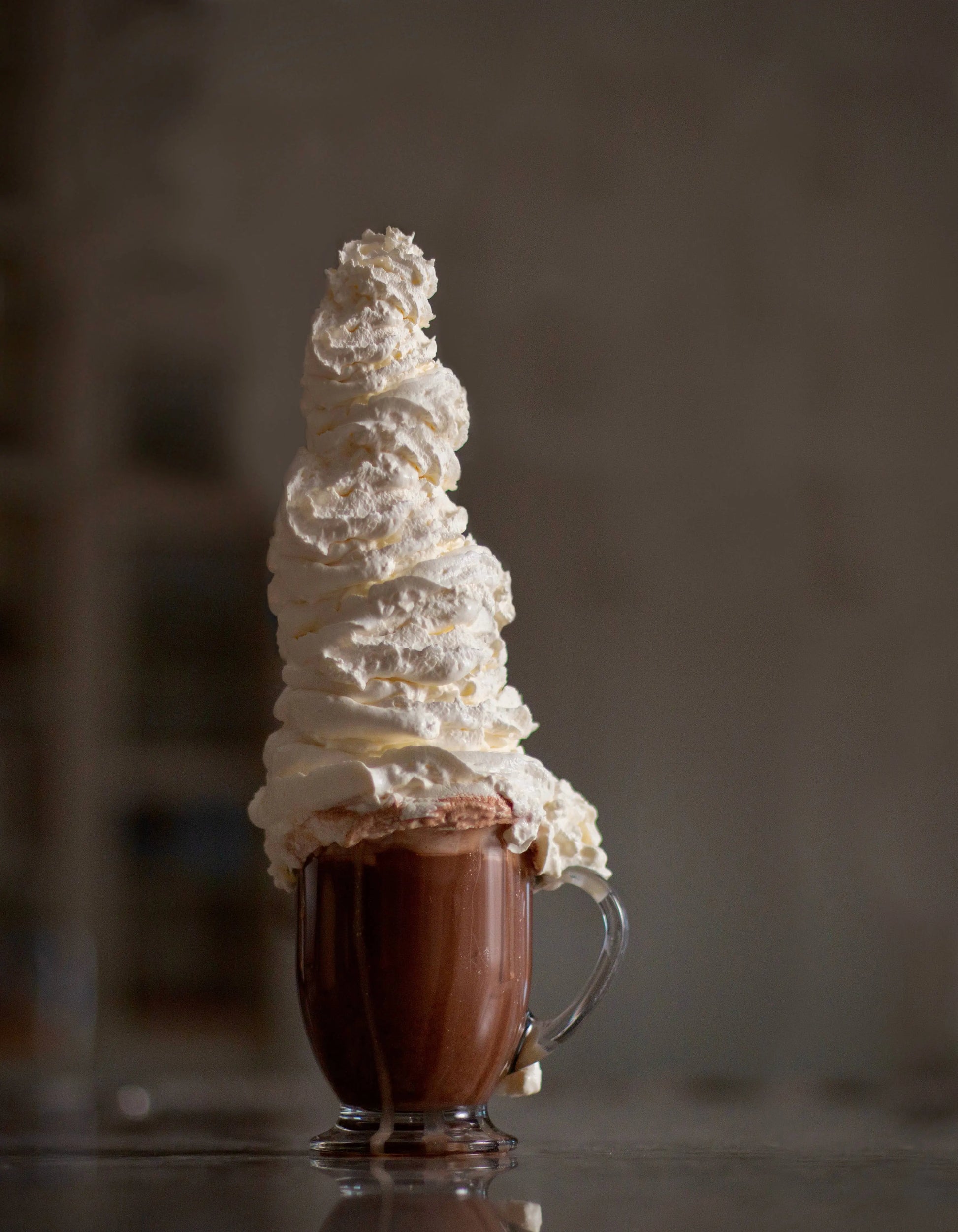 Hot chocolate with a tall tower of whipped cream made with Cocoa Metro Organic Belgian Chocolate mix on a dark background.