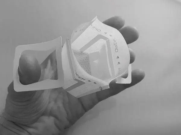 Single serve coffee filter pictured open with side tabs that hold the filter in place over a cup or mug.