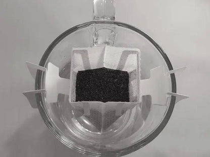 Single serve coffee filter attached to a crystal coffee mug and partially filled with coffee.