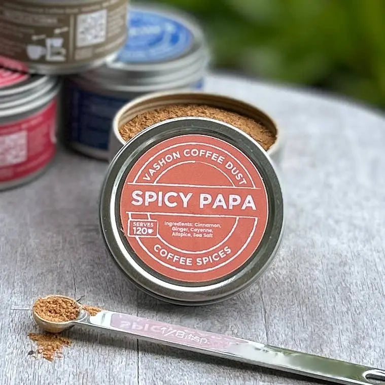 Vashon Island Spicy Papa coffee dust container with a spoonful of ground spices on a wooden surface.
